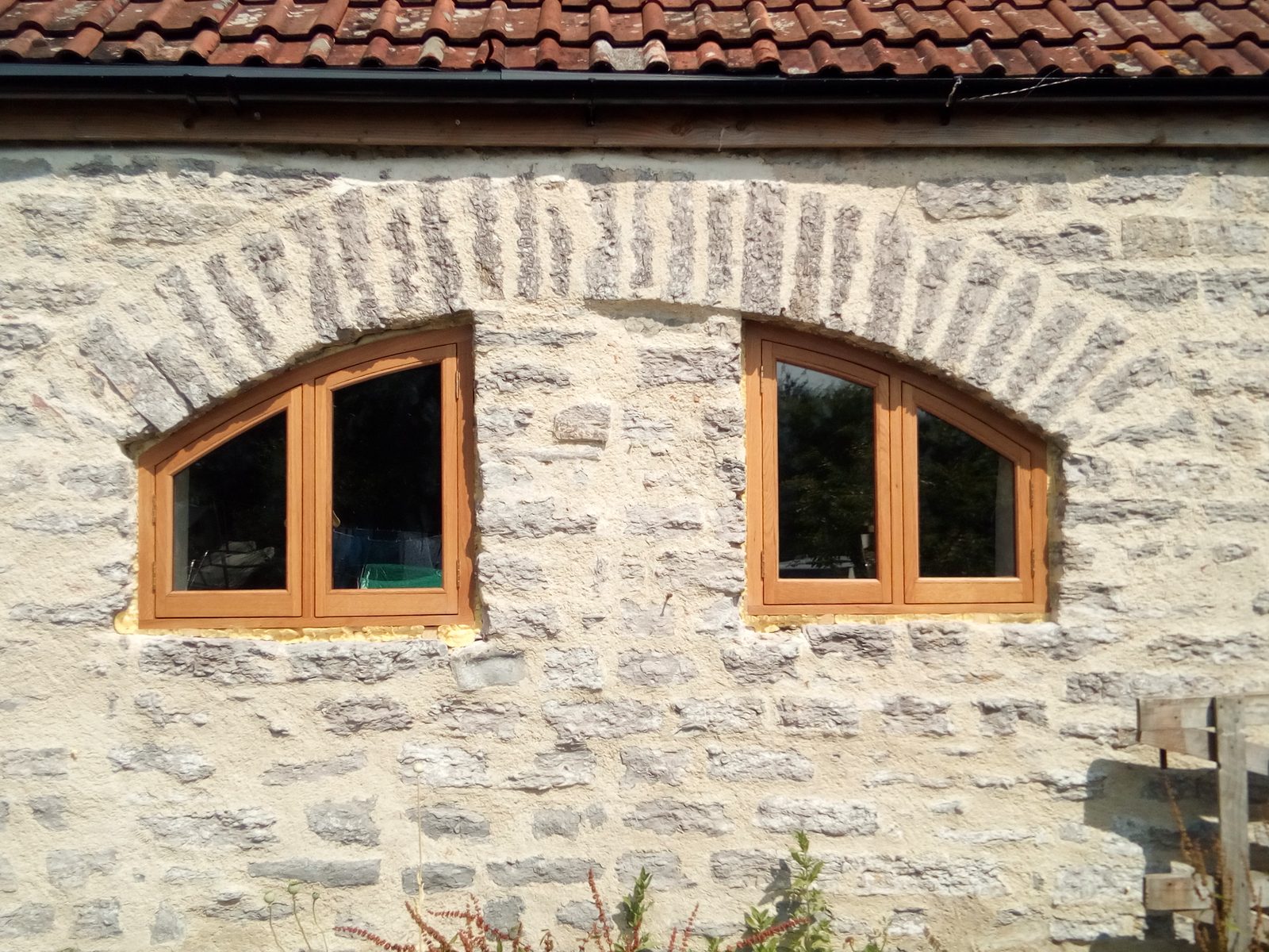 Pair of arched oak windows set in a stone wall