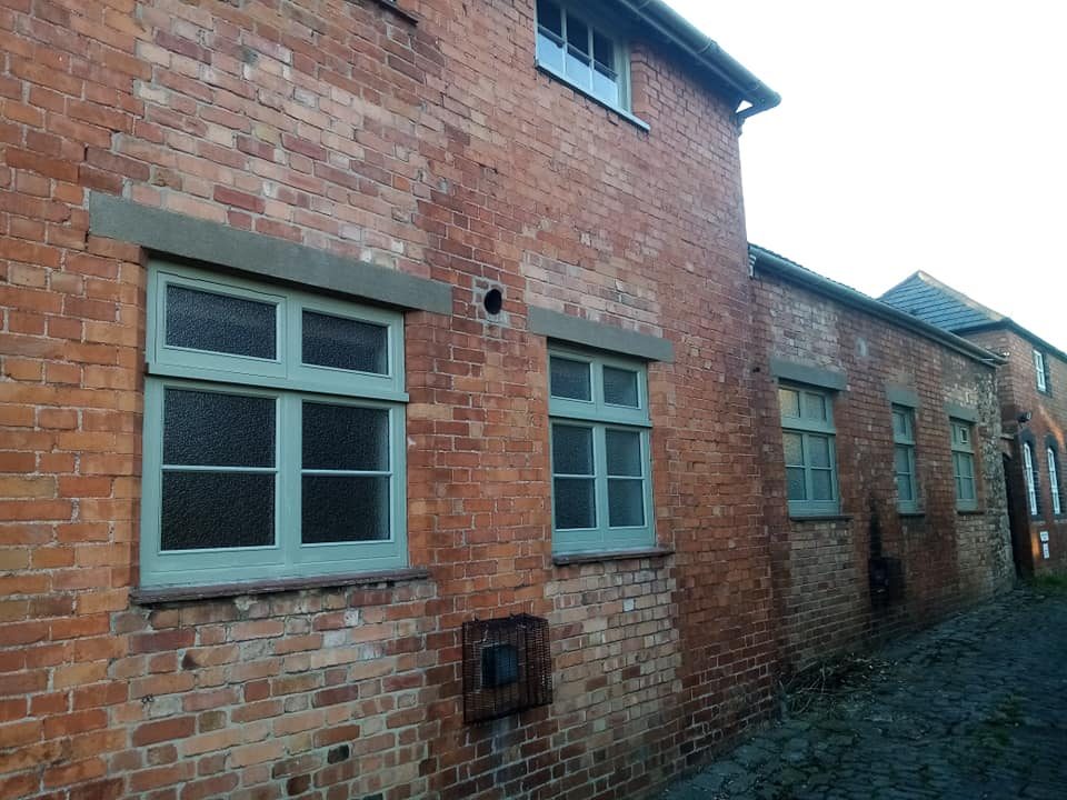Sage green timber window in brickwork